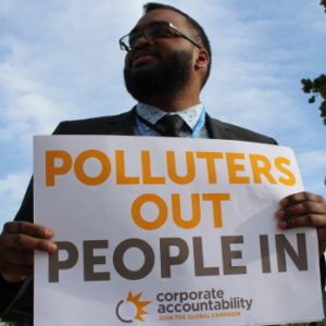 Protester holds "Polluters out, people in" poster