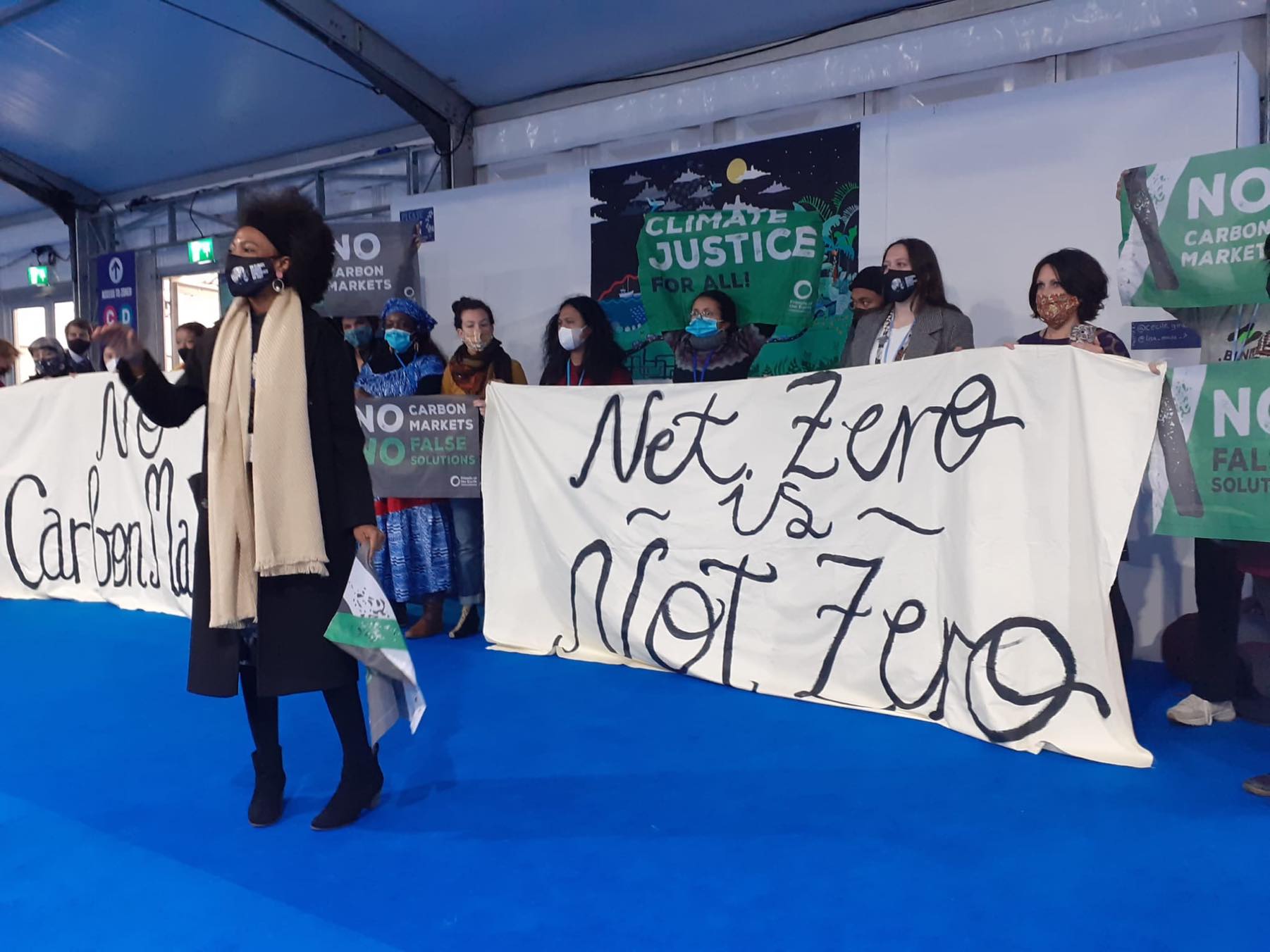 Organizer at COP26 leads an action calling out Big Polluters' "net zero" schemes.